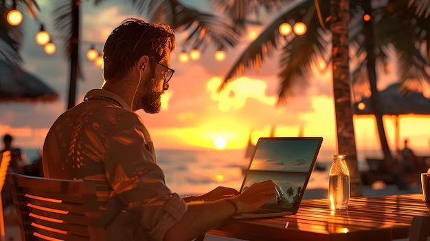 Person using a laptop by the coast
